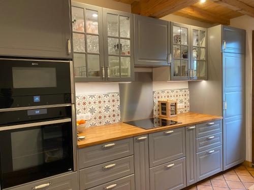 une cuisine avec des placards gris et un comptoir en bois dans l'établissement Le chêne magique 40200 Léontine, à Pontenx-les-Forges