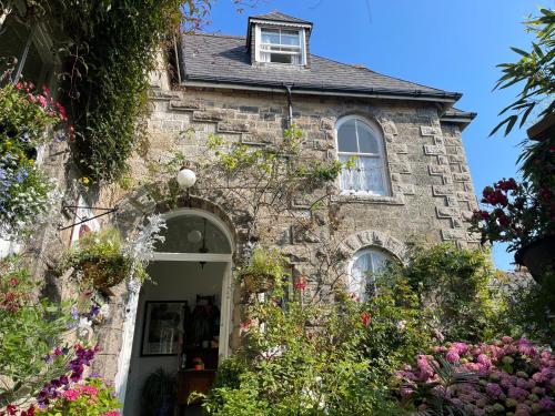 an old stone house with flowers in front of it at Estoril in Penzance