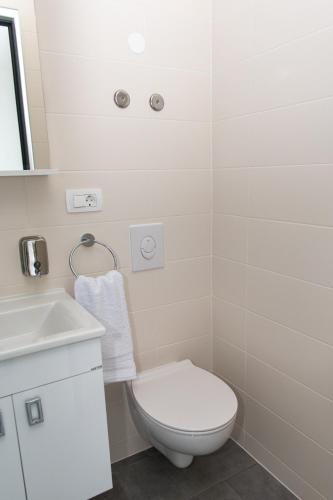 a white bathroom with a toilet and a sink at Prenoćište CMA in Posušje