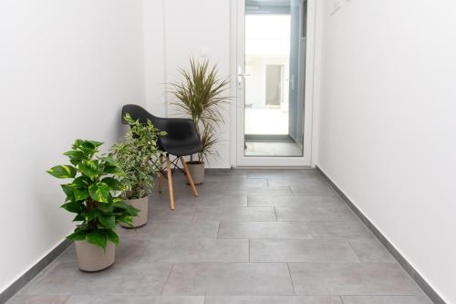 a hallway with potted plants and a black chair at Prenoćište CMA in Posušje