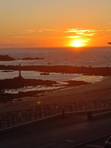 a sunset on the beach with the sun setting over the ocean at Cachinnans Hostel & Apartments in Vila do Conde