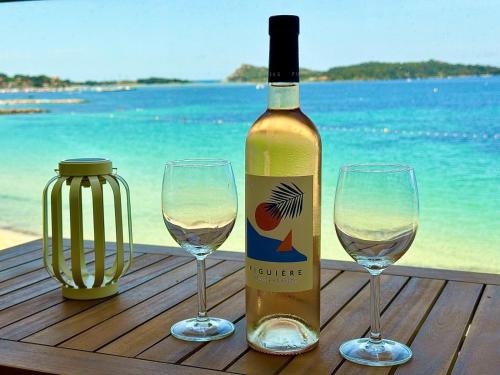 une bouteille de vin et deux verres à vin sur une table dans l'établissement Escapade au Brusc - Les pieds dans l'eau, à Six-Fours-les-Plages