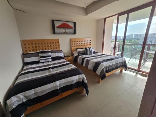 two beds in a room with a large window at Precioso departamento en Acapulco Diamante in Acapulco