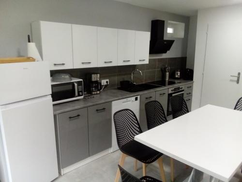 une cuisine avec des placards blancs et une table et des chaises blanches dans l'établissement appt tout confort a laveissiere 103, à Laveissière