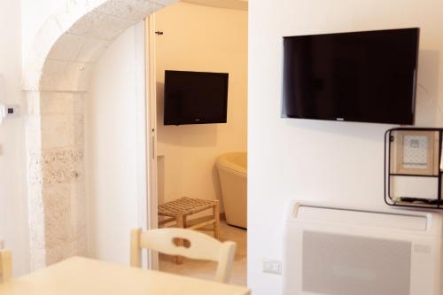 a room with a table and a tv on a wall at Il Trullo di Pozzallegro in Locorotondo