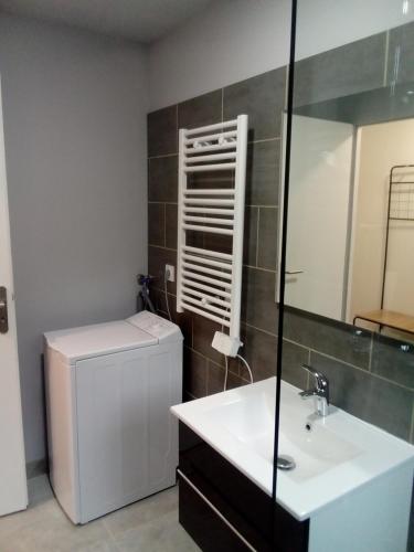 a bathroom with a sink and a refrigerator at appt tout confort a laveissiere 103 in Laveissière