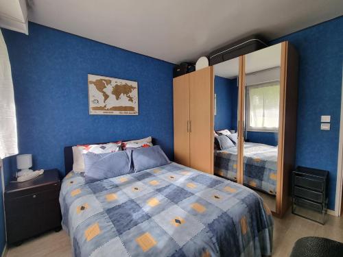 - une chambre bleue avec un lit et un miroir dans l'établissement Chambre avec SDB et Toilettes privatives, à Rosny-sous-Bois