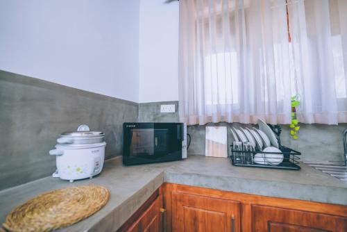 a kitchen with a counter top with a microwave and a tv at Villa Sewinro in Talpe