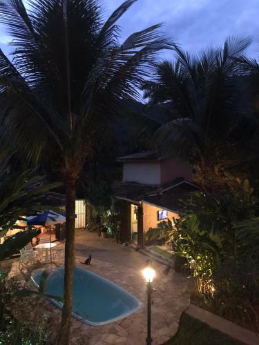 a palm tree and a swimming pool at night at Refúgio do Kairós in Ubatuba