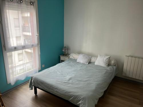 un lit dans une chambre avec un mur bleu dans l'établissement Studio et box 2 arrêts tram Partdieu, 4 du Groupama Stadium avec le tramway T3, à Villeurbanne