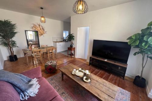 un salon avec un canapé, une télévision et une table dans l'établissement Appartement Le Souffle de l’Orge, à Mortagne-au-Perche