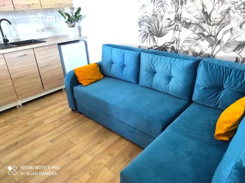 un canapé bleu avec des coussins jaunes dans un salon dans l'établissement Bursztynowe Zacisze Domek 2 Chłopy ul Turystyczna 6, à Chłopy
