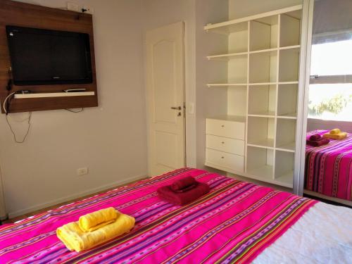 a bedroom with a bed with pink sheets and a tv at Casa de Mar in Puerto Pirámides