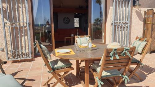 une table et des chaises en bois sur une terrasse dans l'établissement Plage Miramar, à La Londe-les-Maures