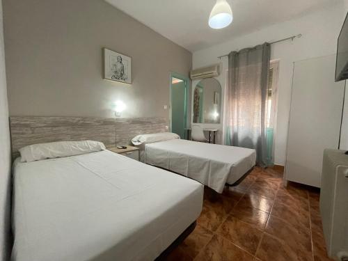 a hotel room with two beds and a window at Pensión Duquesa Bed & Breakfast in Granada