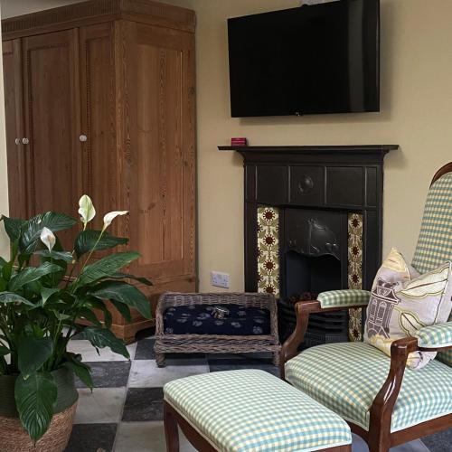 a living room with two chairs and a fireplace at Steeple View - Romantic Wye Valley Country House Studio Apartment - Dog Friendly in Newland