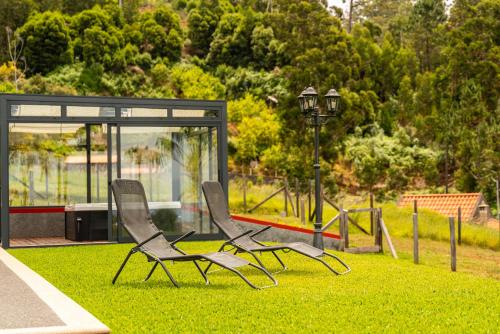 two chairs sitting on the grass in a park at Florenças House - Private Jacuzzi & Garden in Calheta