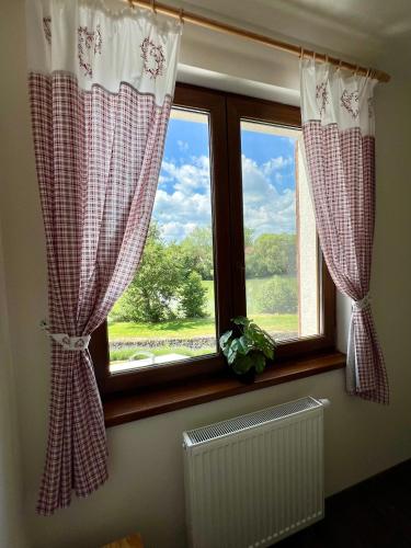 a window with red and white curtains and a radiator at Chalupa nad rybníkem in Straškov