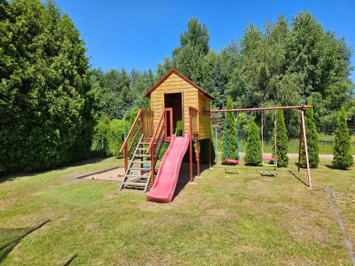 a playground with a slide and a play house at Domki pod gruszą in Kopalino