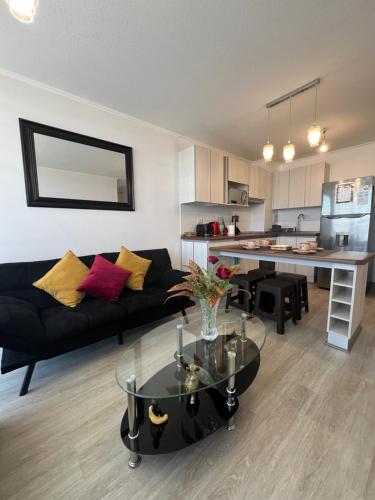 a living room with a black couch and a table at Cómodo departamento a pasos de la playa in La Serena