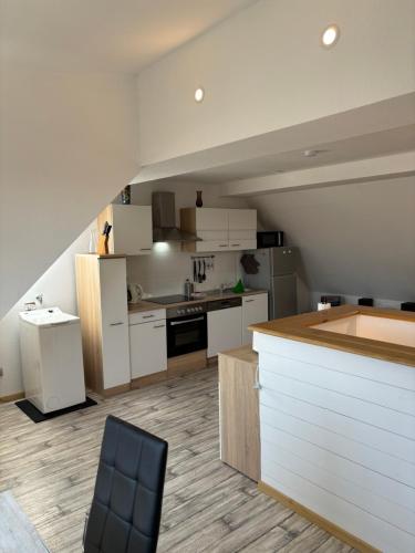 a kitchen with white cabinets and a black chair at Ferienwohnung Bad Frankenhausen in Bad Frankenhausen