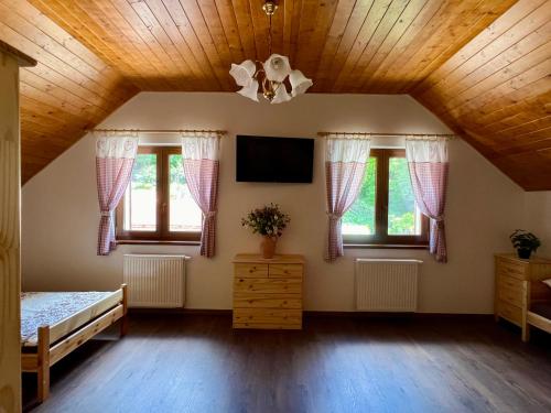 a bedroom with a wooden ceiling and windows at Chalupa nad rybníkem in Straškov