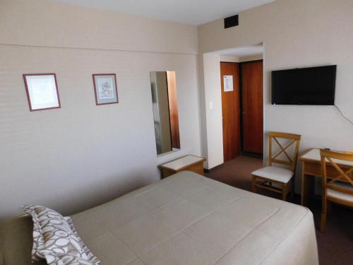 a bedroom with a bed and a desk and a television at Hotel Libertador in Trelew