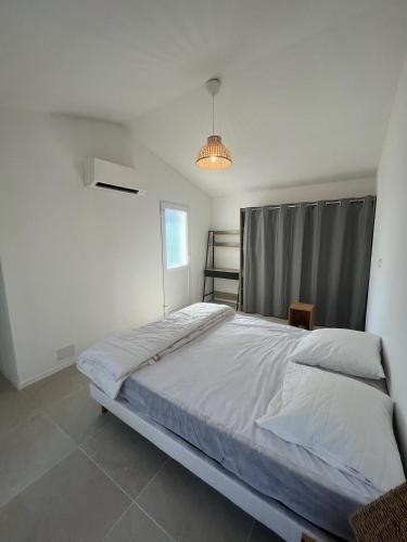 une chambre avec un grand lit dans une pièce blanche dans l'établissement Villa avec piscine, vue dégagée sur la forêt, à Fuveau