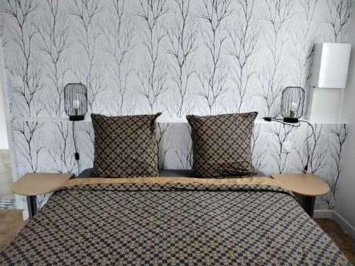 une chambre avec un lit avec deux oreillers et un papier peint dans l'établissement Maison 8 personnes vue sur le Mont Saint Michel, à Huisnes-sur-Mer