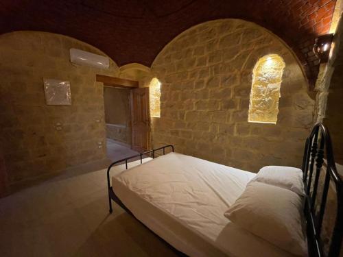 a bedroom with a bed in a stone wall at Hoopoe lodge in Tunis