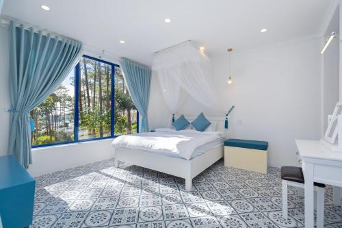 ein weißes Schlafzimmer mit einem Bett und einem Schreibtisch in der Unterkunft Villa Hồ Tuyền Lâm Đà Lạt View Rừng Thông Đà Lạt in Xuan An