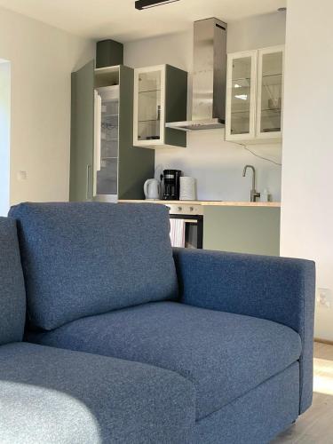 a blue couch in a living room with a kitchen at Dom pod brzozami in Kierwik