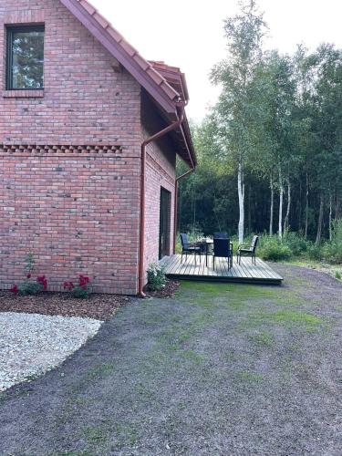 a brick building with a deck with two chairs and a table at Dom pod brzozami in Kierwik