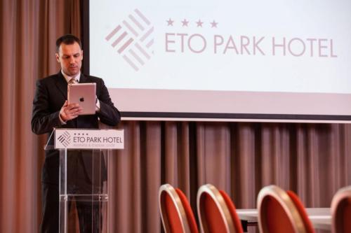 a man standing in front of a podium with a laptop at ETO Park Hotel Business & Stadium in Győr