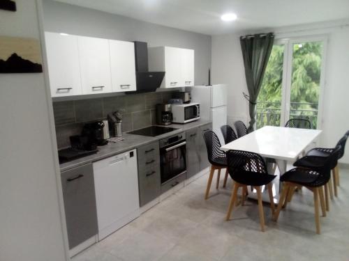 une cuisine avec des armoires blanches et une table et des chaises dans l'établissement appt tout confort à laveissiere 101, à Laveissière