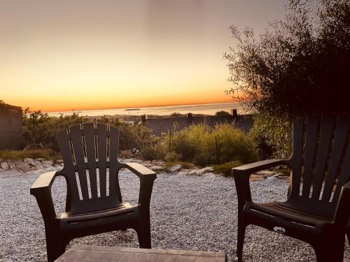 two chairs sitting on a table with the sunset in the background at Gite proche mer in Cherbourg en Cotentin