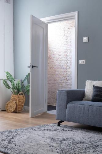 a living room with a blue couch and a brick wall at Het Monumentje in Enkhuizen