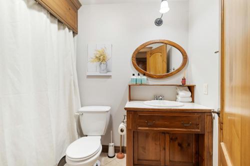 a bathroom with a toilet and a sink and a mirror at Les Manoirs Wpool & Hot Tub Near Village 120-7 in Mont-Tremblant
