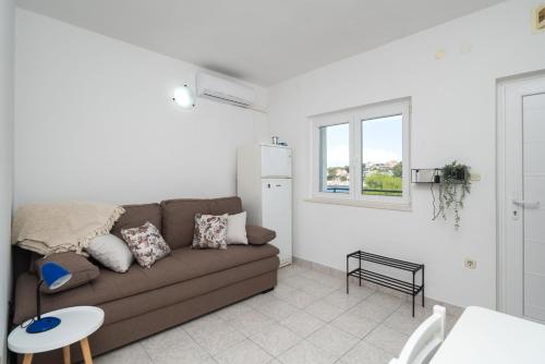 a living room with a brown couch and a window at Apartments Ivica in Primošten