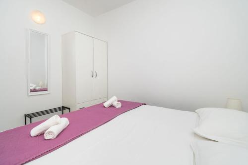 a white bedroom with a bed with towels on it at Apartments Ivica in Primošten