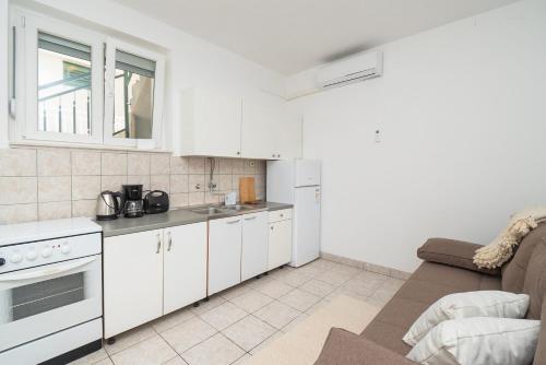 a kitchen with white cabinets and a couch at Apartments Ivica in Primošten