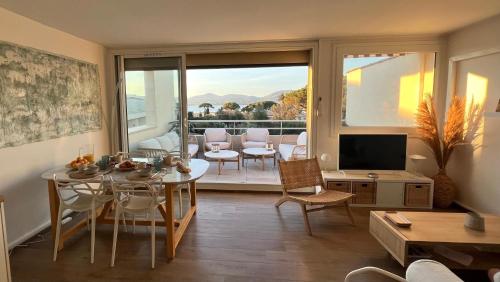 un salon avec une table et une télévision dans l'établissement Terrasse Vue Mer - Appartement 6 pers, 3 chambres et Parking à St Tropez, à Saint-Tropez