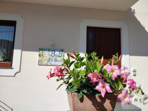 a vase filled with pink flowers in front of a door at San Nicola in Agerola