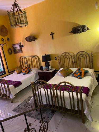 a bedroom with two beds and a cross on the wall at Ekléctic Hotel Boutique in Guadalajara