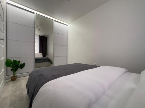a white bedroom with a bed and a mirror at Apartament EROS Rynek in Bolesławiec