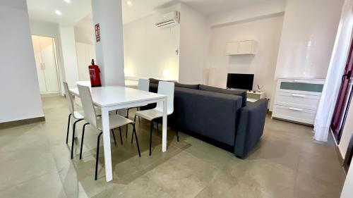 a living room with a white table and a blue couch at Apartamentos Pintor Losada in Córdoba