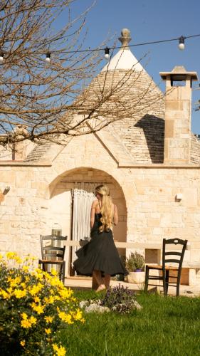 a woman in a black dress standing in front of a building at Trullo Natù - private villa in Alberobello