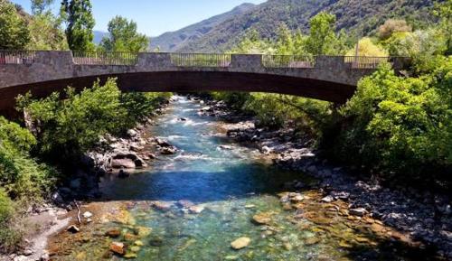 a bridge over a river with a river at Apartaments Sort Pirineus in Sort