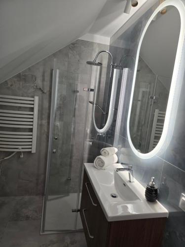 a bathroom with a sink and a shower with a mirror at Apartments Orkana Street in Oborniki Śląskie