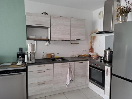 une cuisine avec des armoires en bois et un réfrigérateur dans l'établissement Appartement T2 avec terrasse, 5 min de la plage, à Fréjus
